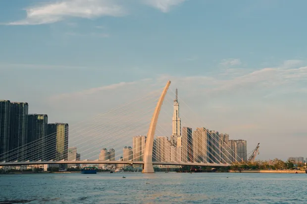 Cầu Ba Son bắc qua sông Sài Gòn lúc hoàng hôn, phía sau là các tòa tháp ven sông và Landmark 81.