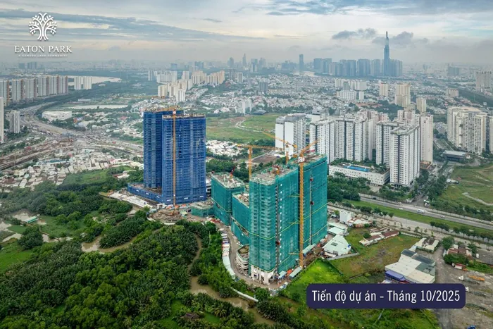 Ảnh chụp tiến độ Eaton Park từ trên cao, tháng 10 năm 2025. Strait và Grove vươn lên dưới lưới xanh dương bên trái, các tháp lưới xanh lá đang lên tầng, đường chân trời thành phố phía sau.